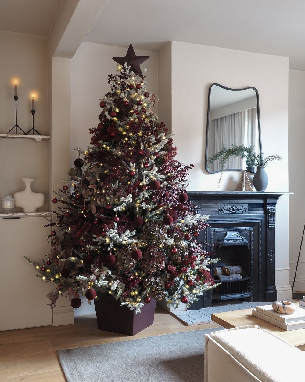 Burgundy Christmas tree beside a fireplace